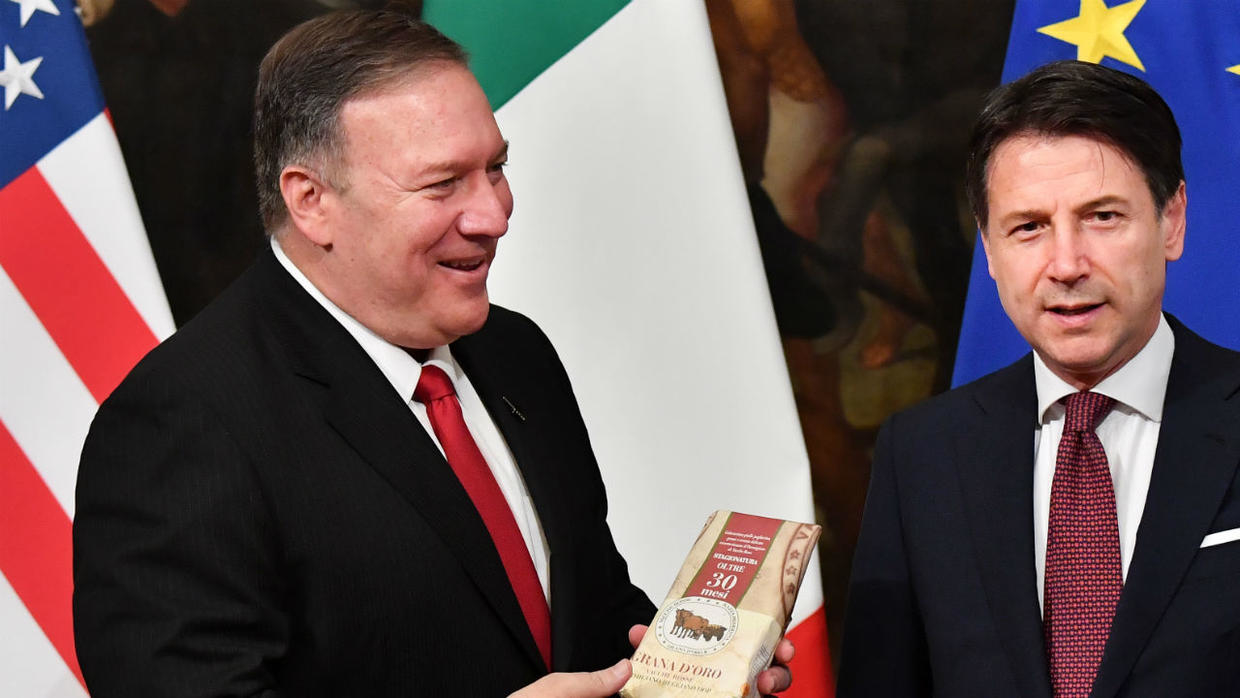 Le secrétaire d'État américain, Mike Pompeo, reçoit un morceau de fromage italien offert par un journaliste, lors de sa conférence de presse avec le Premier ministre italien, Giuseppe Conte, le 1er octobre à Rome